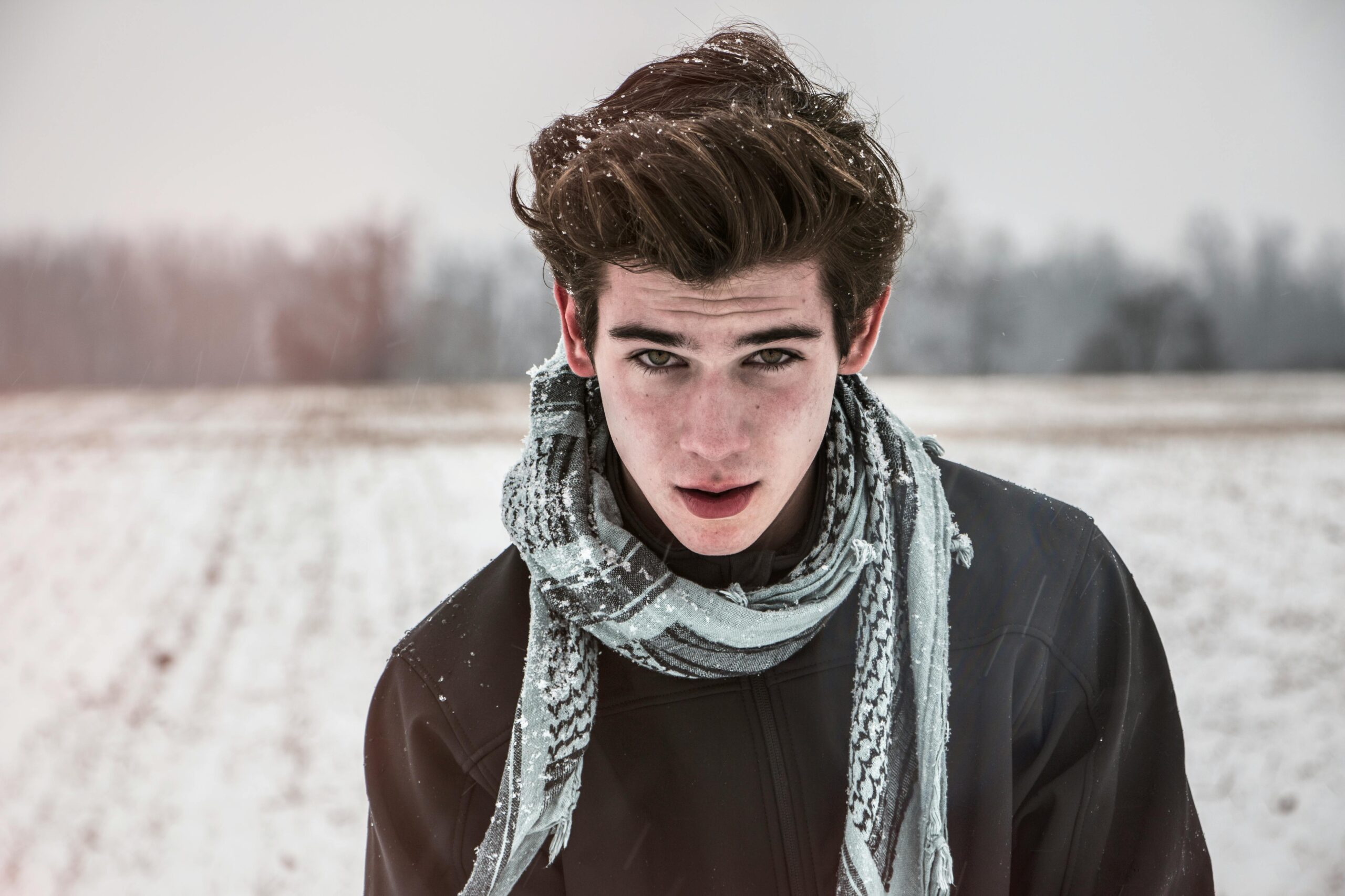 A young boy standing on a snowy hill, looking curious and asking, 'What does it mean when someone looks at you and their pupils get bigger?