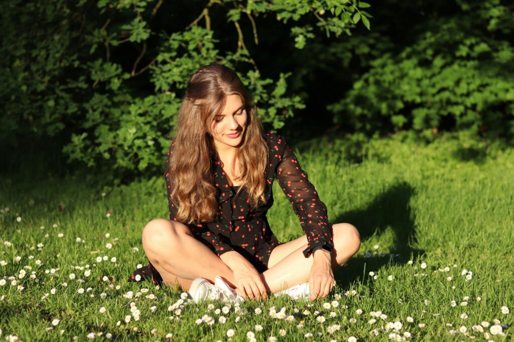 A girl sitting on the grassy ground.