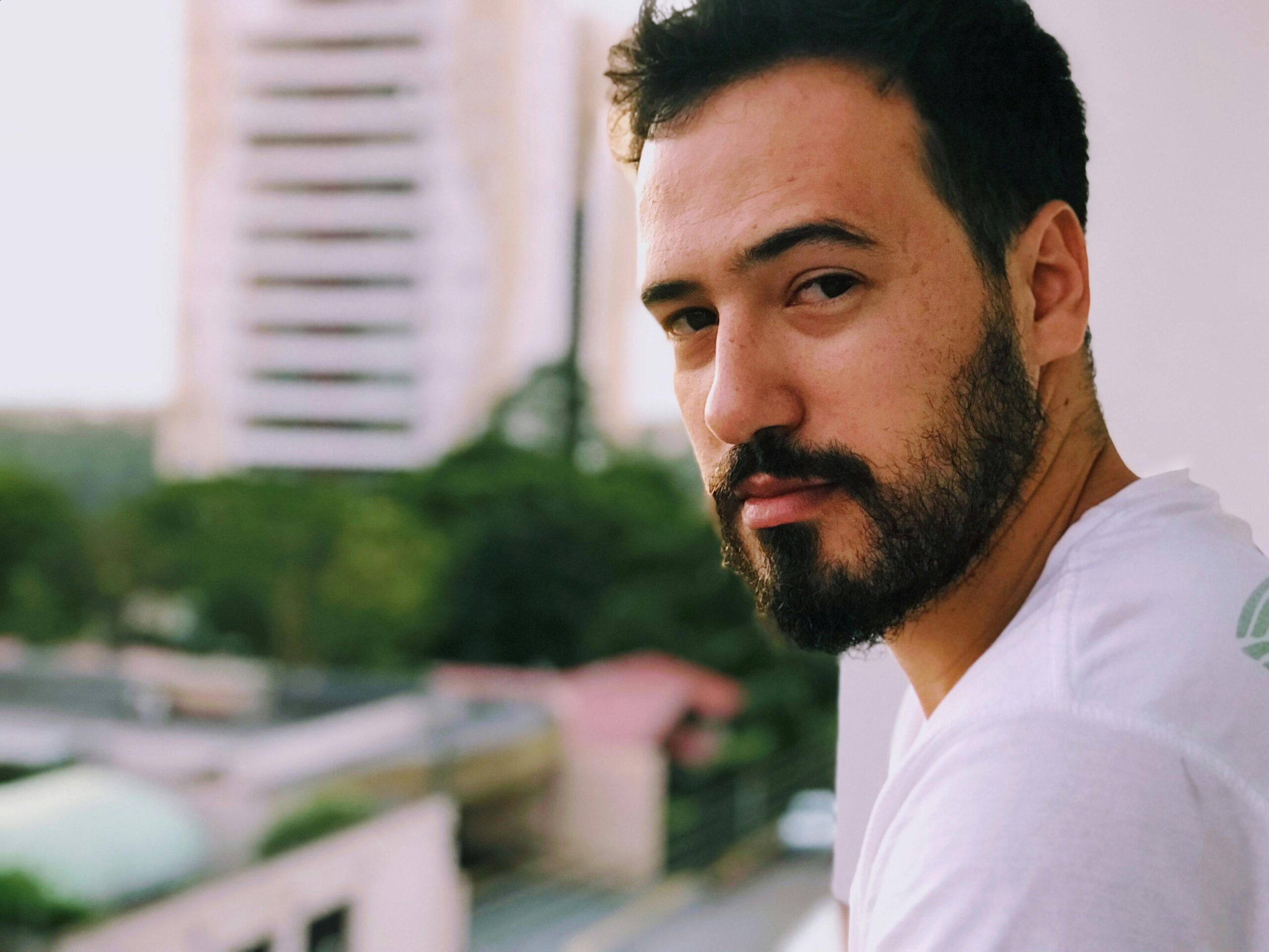 A man standing on a balcony, asking 'What does it mean when someone stares at you all the time?'