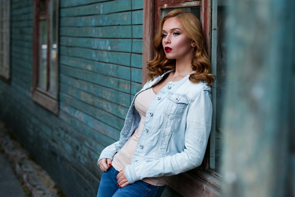 A girl standing along a wall, staring at someone without blinking.