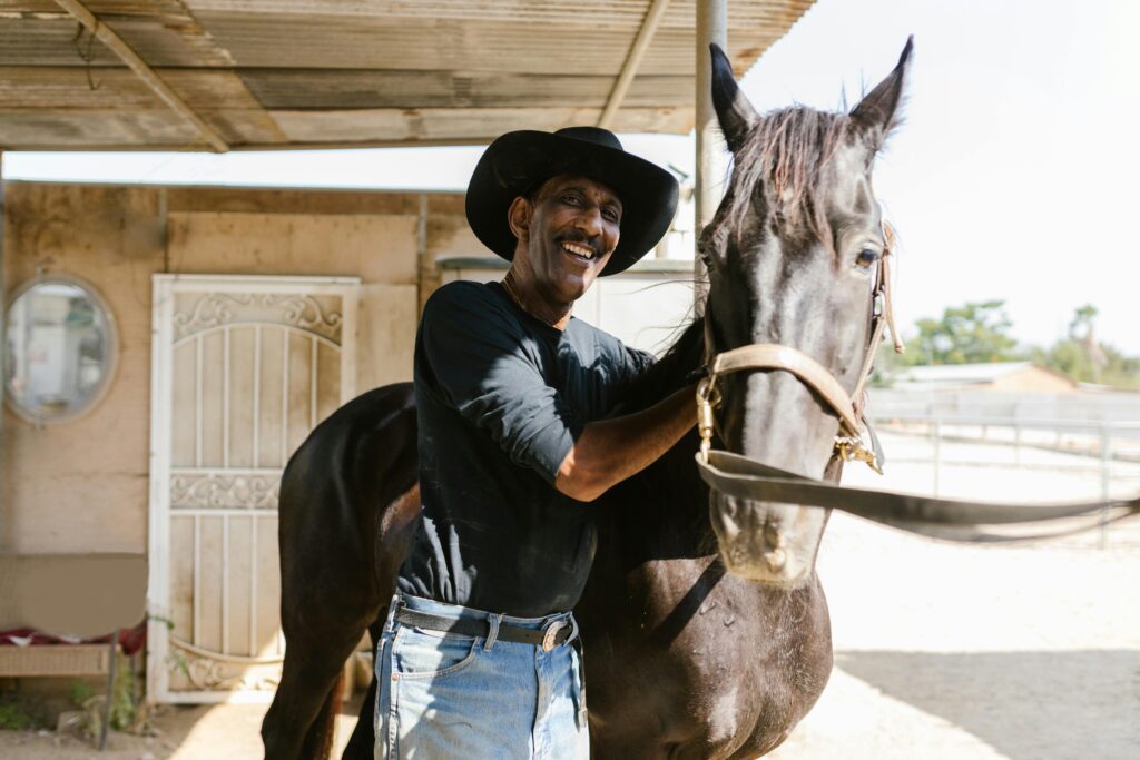 A cowboy standing proudly with his horse.