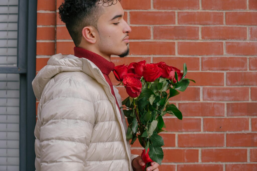 A boy holding red flowers in his hand, eagerly waiting for his girlfriend.