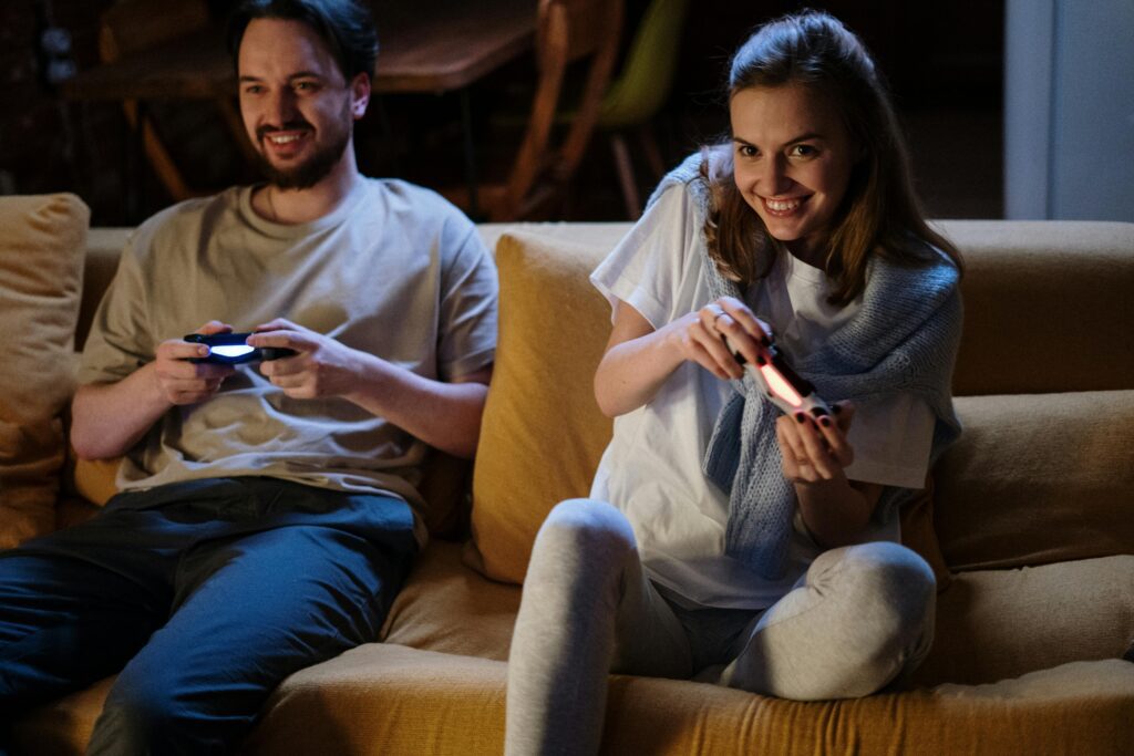 A couple sitting on a sofa, enjoying a game together.