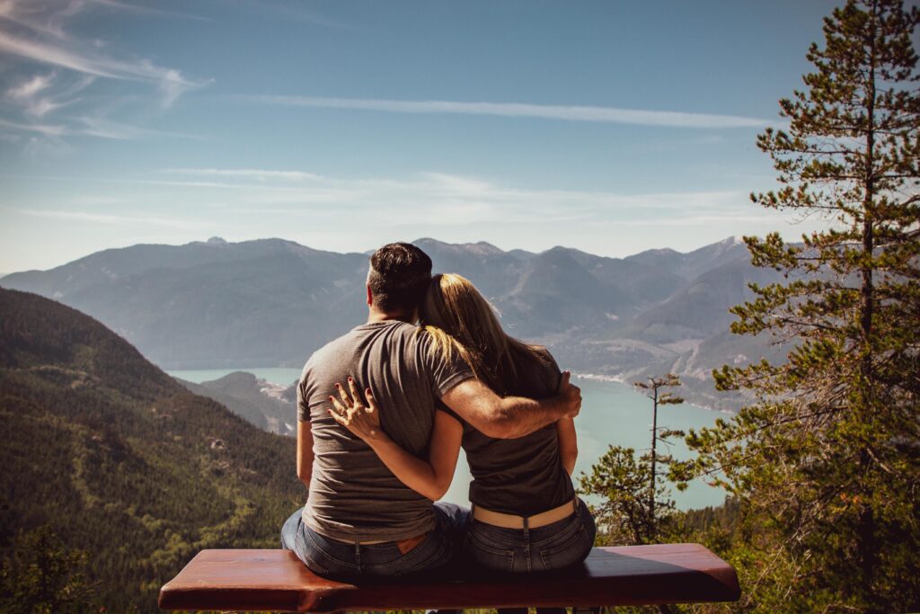 A couple sitting together on a hill station, enjoying the scenic view.