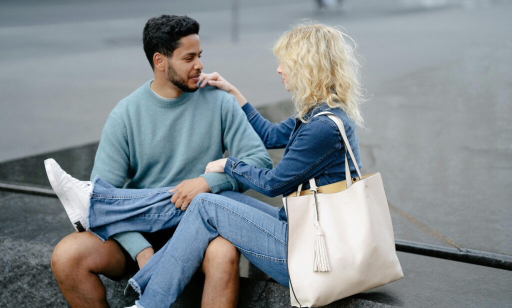 A couple sitting on the beach, engaged in conversation.