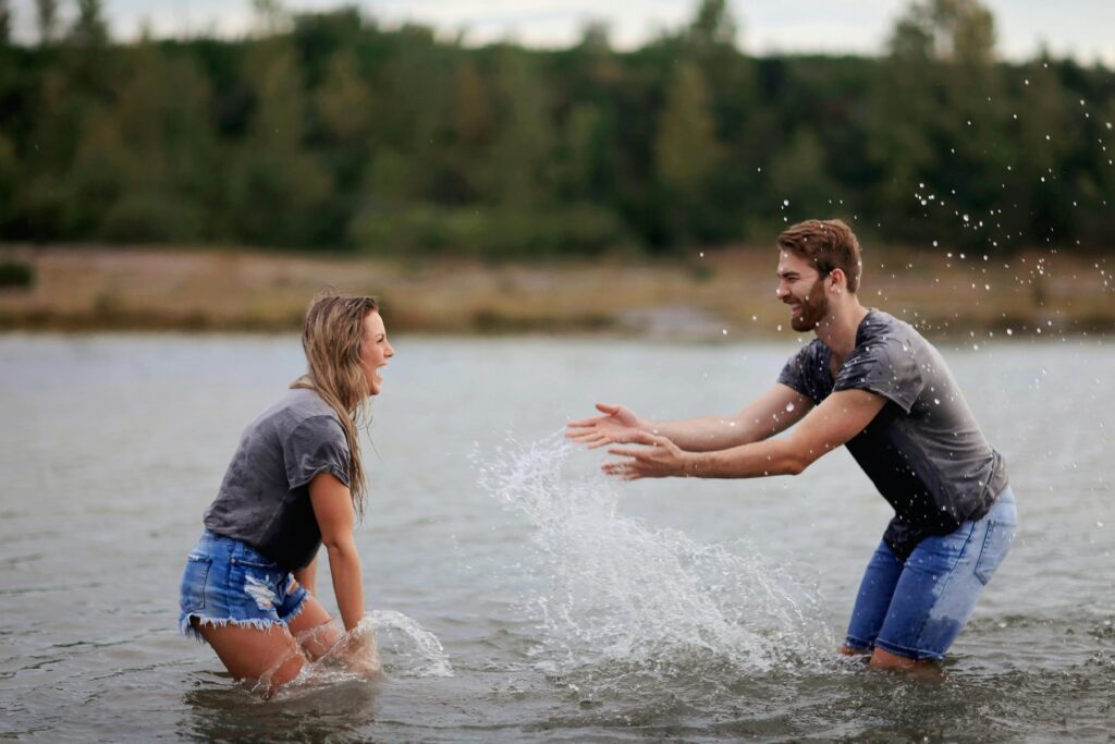 A couple playing in the river water, smiling and enjoying themselves.