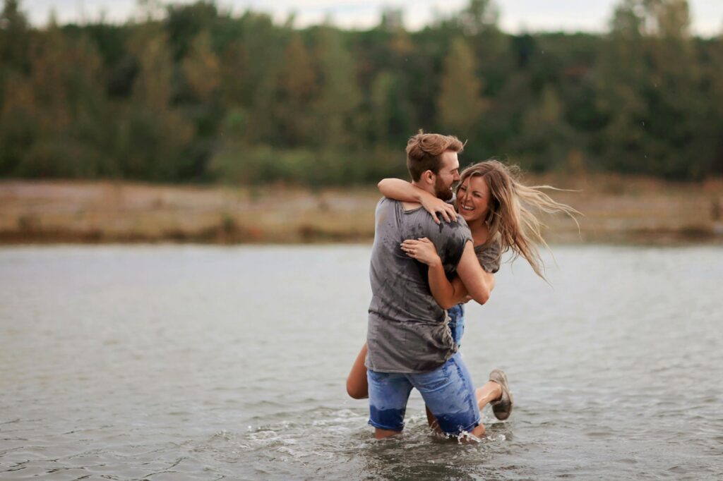 A couple cuddling in the water while playing, sharing a joyful moment together.