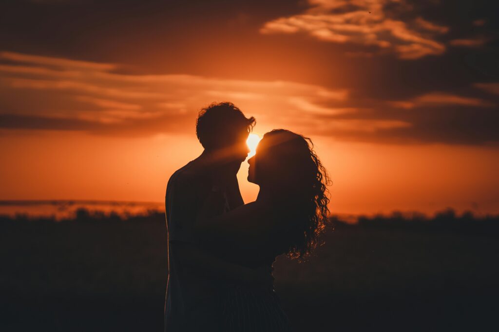 A picturesque sunset scene with a couple sharing a moment of love.