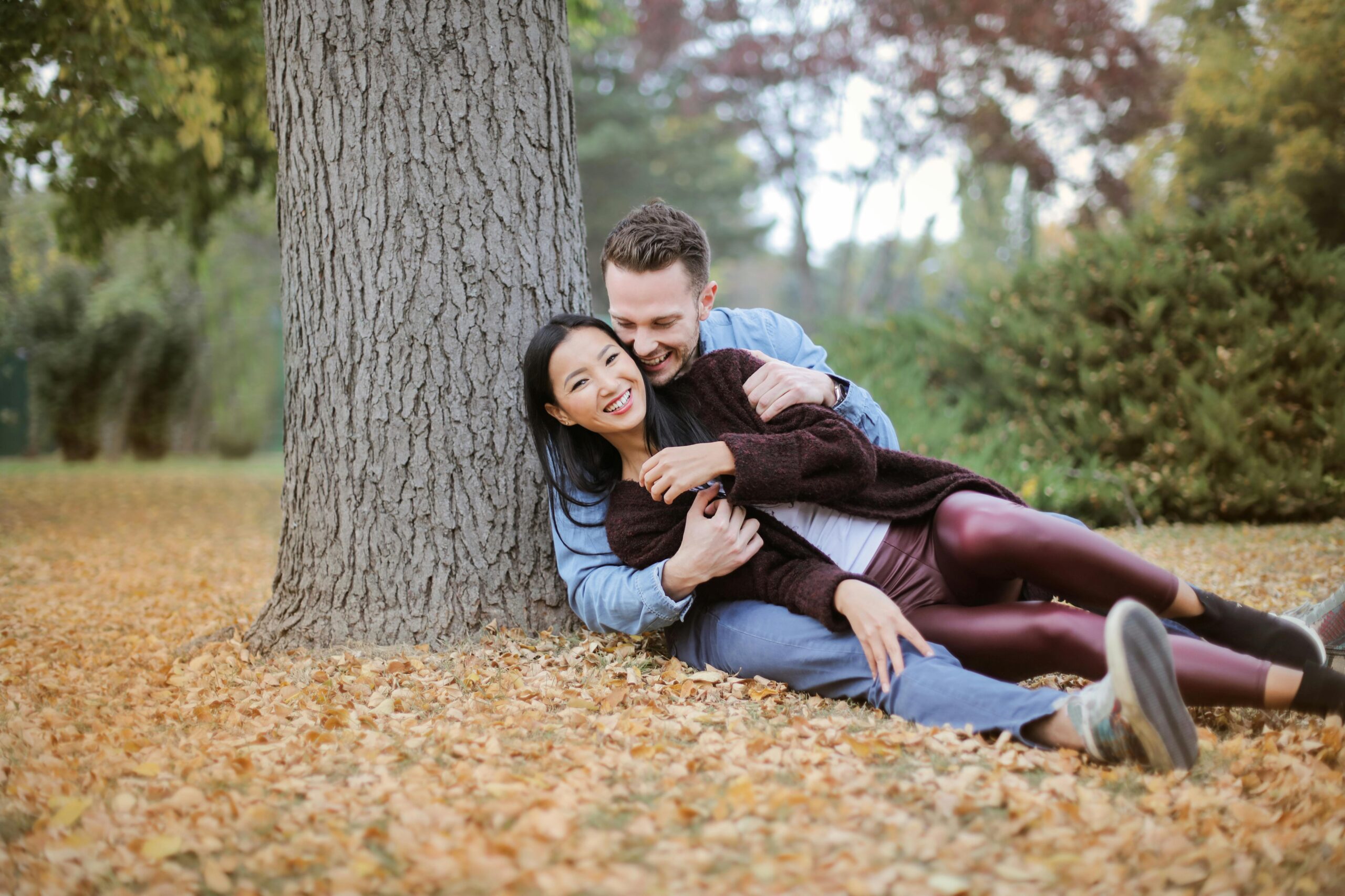 A couple sitting together in a forest, enjoying each other's company and wondering about the meaning when a guy says he has plans.