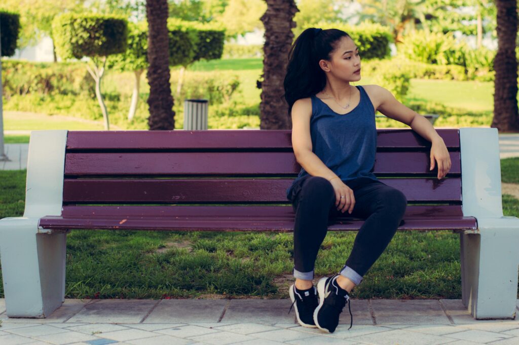 A girl sitting on a bench in the park.